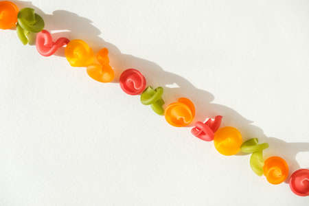 Multicolored pasta lie in line on a white background. Top view. Copy, empty space for text.の写真素材