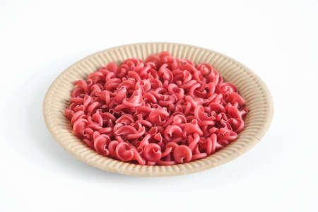 Red pasta in a disposable paper plate on a white background. Copy, empty space for text.の写真素材