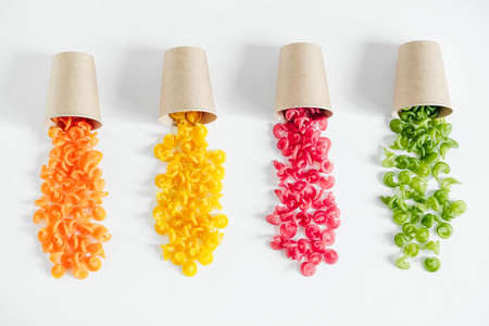 Multicolored pasta in a disposable kraft paper cups scattered on a white background. Top view. Copy, empty space for text.の写真素材