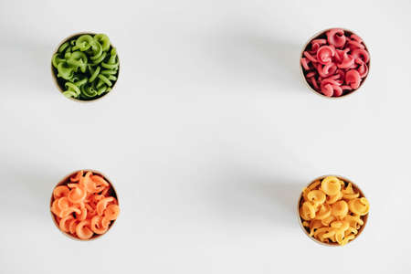 Multicolored pasta in a disposable kraft paper cups scattered on a white background. Top view. Copy, empty space for text.の写真素材