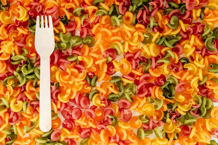 Multicolored pasta with a wooden fork as a background image. Top view. Copy, empty space for text.の写真素材