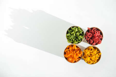 Multicolored pasta in a disposable kraft paper cups scattered on a white background. Top view. Copy, empty space for text.の写真素材