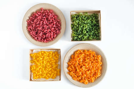 Multicolored pasta in a disposable kraft paper plates and boxes on a white background. Top view. Copy, empty space for text.の写真素材