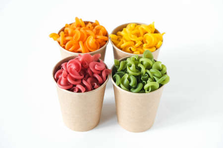 Multicolored pasta in a disposable kraft paper cups scattered on a white background. Top view. Copy, empty space for text.の写真素材