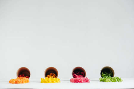 Multicolored pasta in a disposable kraft paper cups scattered on a white background. Top view. Copy, empty space for text.の写真素材