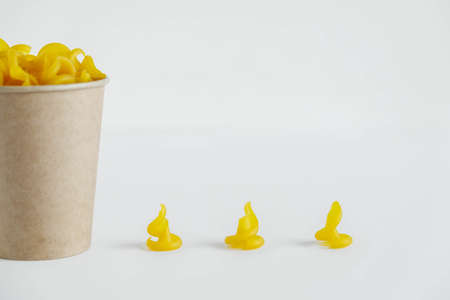 Yellow pasta in a disposable kraft paper cup on a white background. Copy, empty space for text.の写真素材