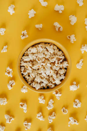 Popcorn in a yellow bowl on a yellow background. Top view. Copy, empty space for text.の写真素材