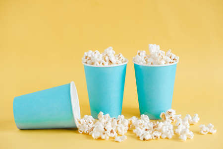Popcorn in blue paper cups on a yellow background. Copy, empty space for text.の写真素材