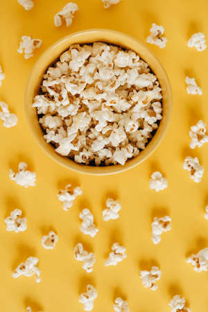 Popcorn in a yellow bowl on a yellow background. Top view. Copy, empty space for text.の写真素材