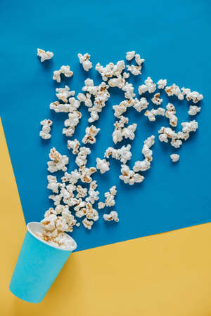 Popcorn in blue paper cups on a yellow and blue background. Top view. Copy, empty space for text.の写真素材