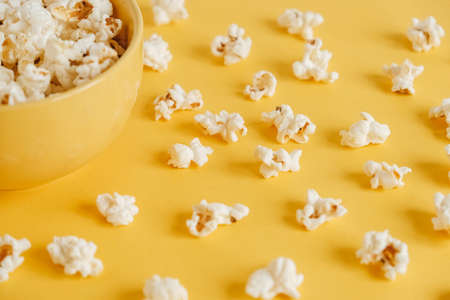 Popcorn in a yellow bowl on a yellow background. Top view. Copy, empty space for text.の写真素材