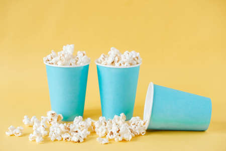 Popcorn in blue paper cups on a yellow background. Copy, empty space for text.の写真素材