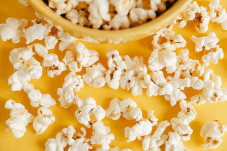 Popcorn in a yellow bowl on a yellow background. Top view. Copy, empty space for text.の写真素材