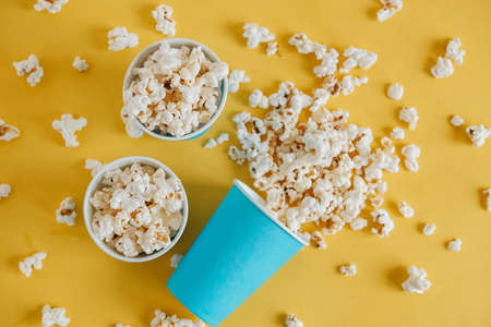 Popcorn in blue paper cups on a yellow background. Top view. Copy, empty space for text.の写真素材