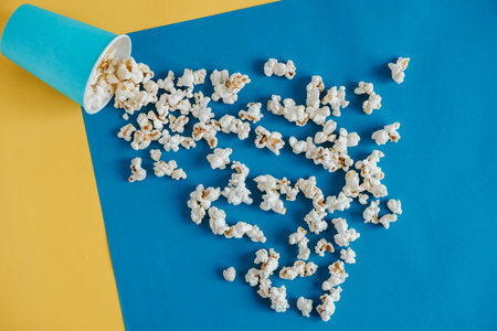 Popcorn in blue paper cups on a yellow and blue background. Top view. Copy, empty space for text.の写真素材