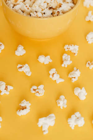 Popcorn in a yellow bowl on a yellow background. Top view. Copy, empty space for text.の写真素材