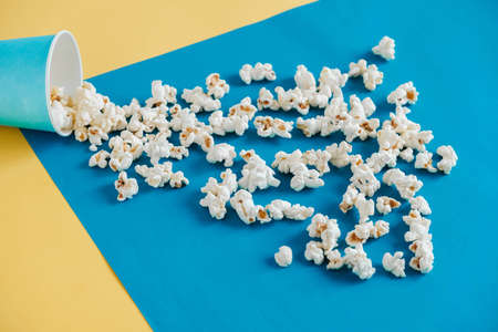Popcorn in blue paper cups on a yellow and blue background. Top view. Copy, empty space for text.の写真素材