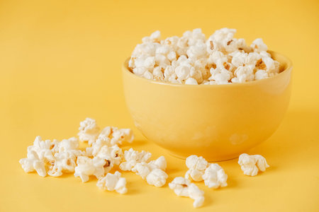 Popcorn in a yellow bowl on a yellow background. Copy, empty space for text.の写真素材