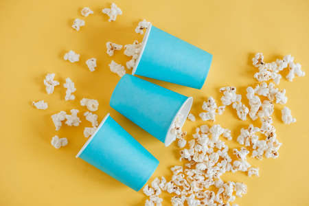 Popcorn in blue paper cups on a yellow background. Top view. Copy, empty space for text.の写真素材