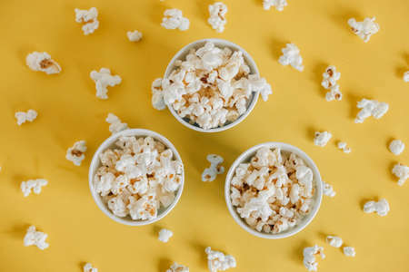 Popcorn in blue paper cups on a yellow background. Top view. Copy, empty space for text.の写真素材