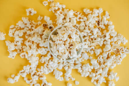 Popcorn in paper cup on a yellow background. Top view. Copy, empty space for text.の写真素材
