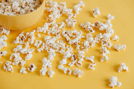 Popcorn in a yellow bowl on a yellow background. Top view. Copy, empty space for text.の写真素材