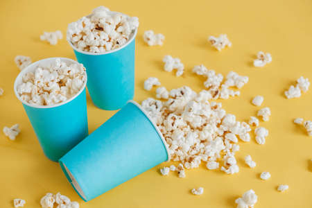 Popcorn in blue paper cups on a yellow background. Top view. Copy, empty space for text.の写真素材