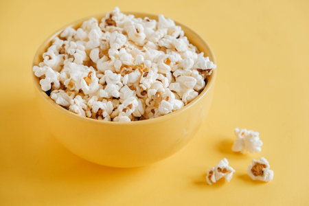 Popcorn in a yellow bowl on a yellow background. Top view. Copy, empty space for text.の写真素材