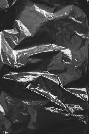 Black crumpled plastic film as a background texture image. Top view. Copy, empty space for text.の写真素材