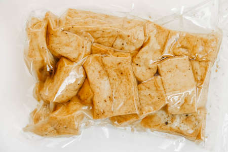Tofu with spices in a plastic package on a white background. Top view. Copy, empty space for text.の写真素材