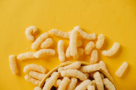 Corn sticks in a yellow bowl on a yellow background. Top view. Place for your text.の写真素材