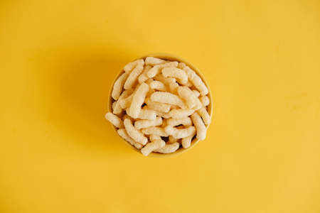 Corn sticks in a yellow bowl on a yellow background. Top view. Place for your text.の写真素材