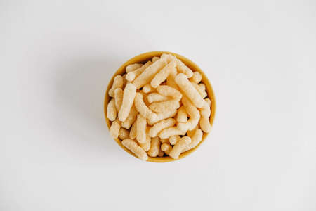 Corn sticks in a yellow bowl on a white background. Top view. Place for your text.の写真素材