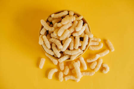 Corn sticks in a yellow bowl on a yellow background. Top view. Place for your text.の写真素材