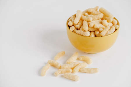 Corn sticks in a yellow bowl on a white background. Place for your text.の写真素材