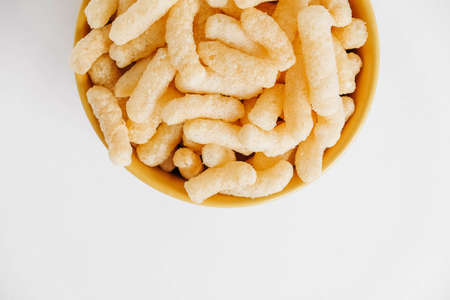 Corn sticks in a yellow bowl on a white background. Top view. Place for your text.の写真素材