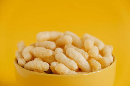 Corn sticks in a yellow bowl on a yellow background. Copy, empty space for text.の写真素材