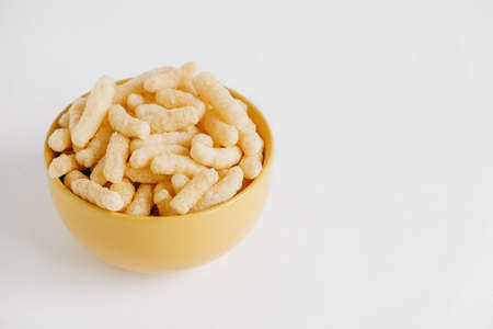 Corn sticks in a yellow bowl on a white background. Place for your text.の写真素材