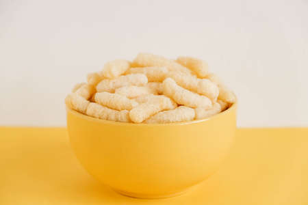 Corn sticks in a yellow bowl on a yellow background. Copy, empty space for text.の写真素材
