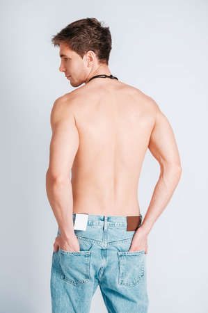 Young muscular man in a light T-shirt and black jeans on a white background. Copy, empty space for text.の写真素材