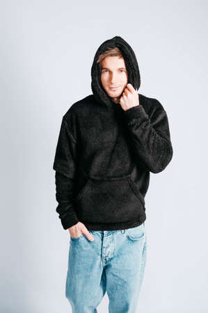 Young muscular man in a light T-shirt and black jeans on a white background. Copy, empty space for text.の写真素材