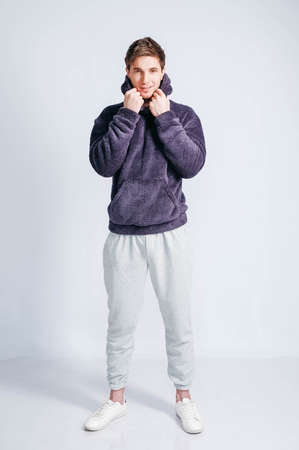 Young muscular man in a light T-shirt and black jeans on a white background. Copy, empty space for text.の写真素材