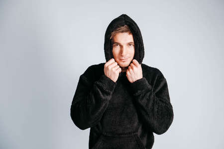 Young muscular man in a light T-shirt and black jeans on a white background. Copy, empty space for text.の写真素材