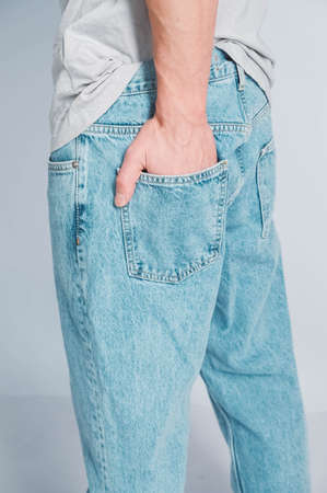 Young muscular man in a light T-shirt and black jeans on a white background. Copy, empty space for text.の写真素材