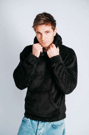 Young muscular man in a light T-shirt and black jeans on a white background. Copy, empty space for text.の写真素材