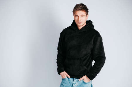 Young muscular man in a light T-shirt and black jeans on a white background. Copy, empty space for text.の写真素材