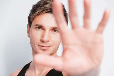 Young muscular man in a light T-shirt and black jeans on a white background. Copy, empty space for text.の写真素材