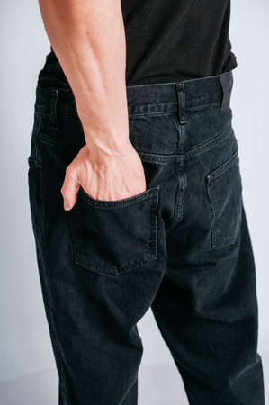 Young muscular man in a light T-shirt and black jeans on a white background. Copy, empty space for text.の写真素材