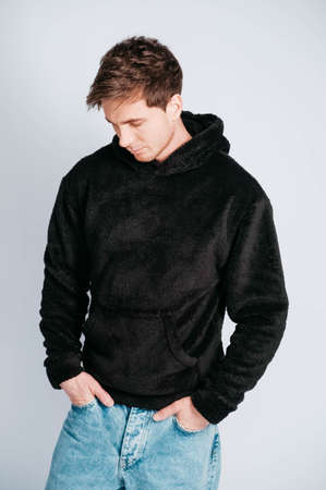 Young muscular man in a light T-shirt and black jeans on a white background. Copy, empty space for text.の写真素材