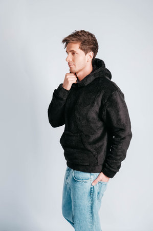 Young muscular man in a light T-shirt and black jeans on a white background. Copy, empty space for text.の写真素材